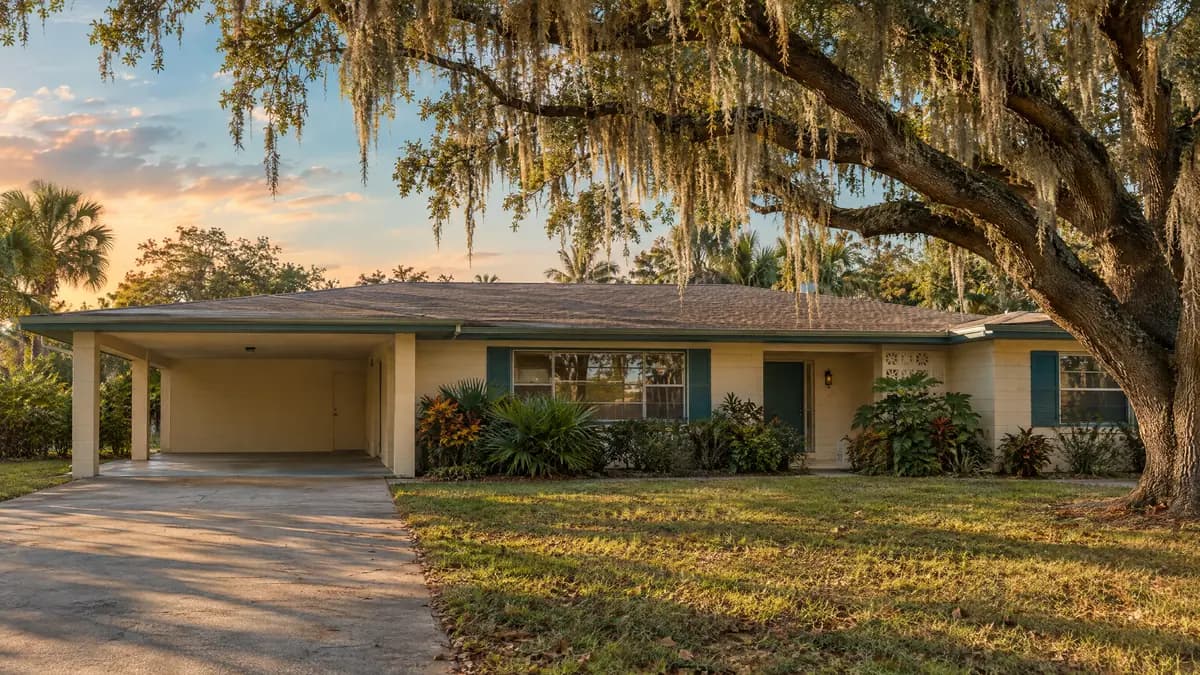 Older single-story Florida ranch home with a carport under a live oak