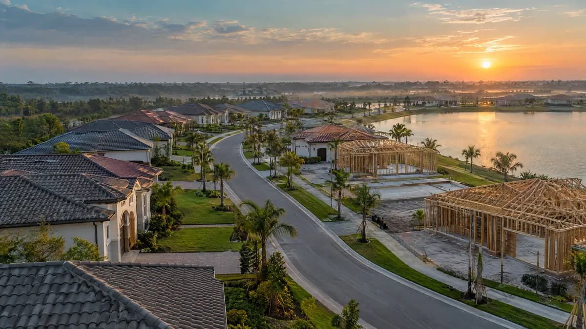 New Florida neighborhood with finished homes beside houses still being framed, next to a lake